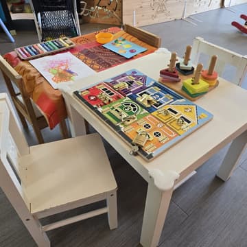 Table d'atelier avec un dessin, un collage de gommettes et des craies